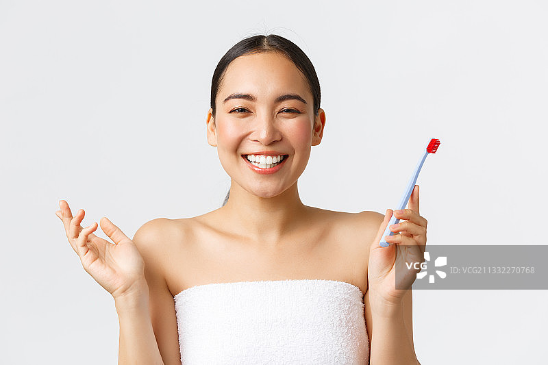 微笑的年轻女子手持画笔在灰色背景前图片素材