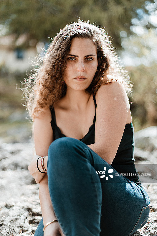 年轻女子坐在岩石上，卡哈马卡，秘鲁图片素材