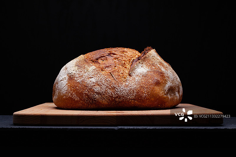 黑色背景下，砧板上的面包特写图片素材