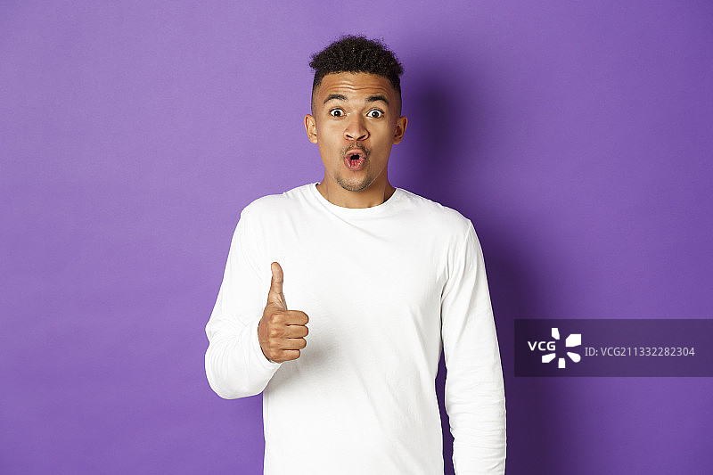 在紫色背景前做手势的年轻男人肖像图片素材
