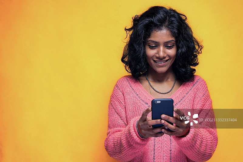在意大利黄色背景下使用手机的年轻女子图片素材