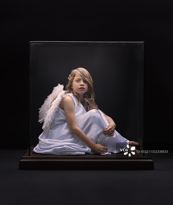 年轻女子坐在黑色背景前的椅子上的肖像照图片素材