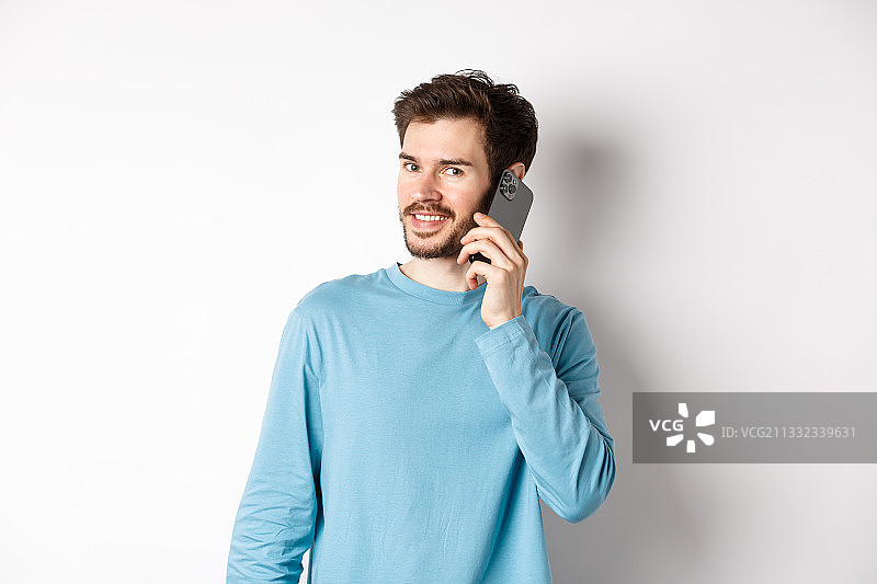 靠在白色背景上用手机交谈的微笑年轻人图片素材