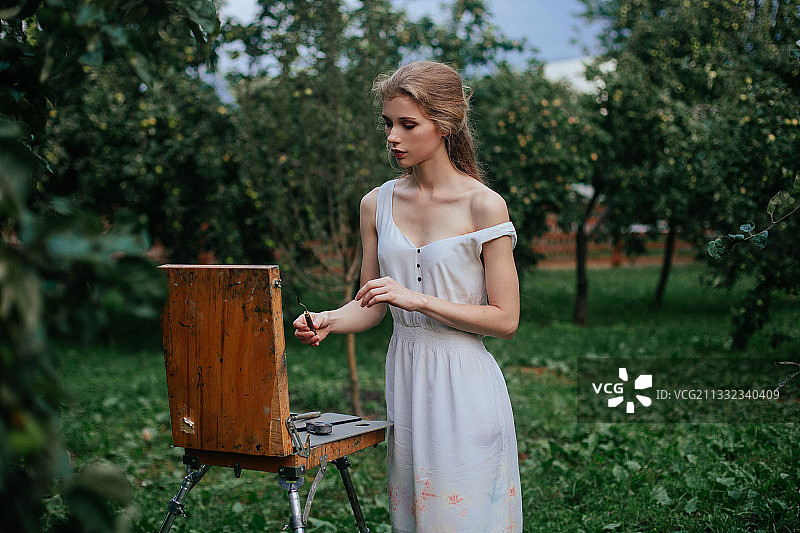 在俄罗斯田野上绘画的年轻女人图片素材