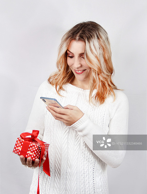 笑容灿烂的年轻女子手持礼品盒，背景为白色图片素材