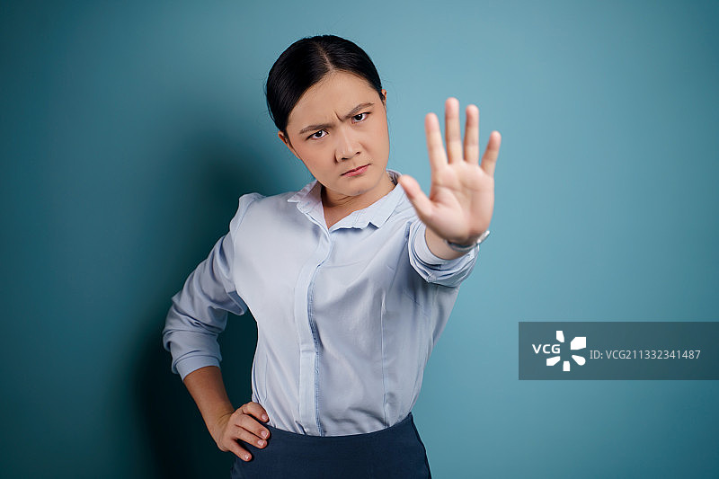 以蓝色为背景，做手势的女商人肖像图片素材