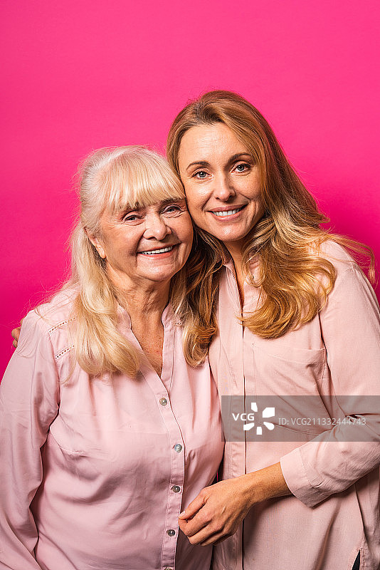 粉色背景上的中年妇女和年长母亲的全家福图片素材