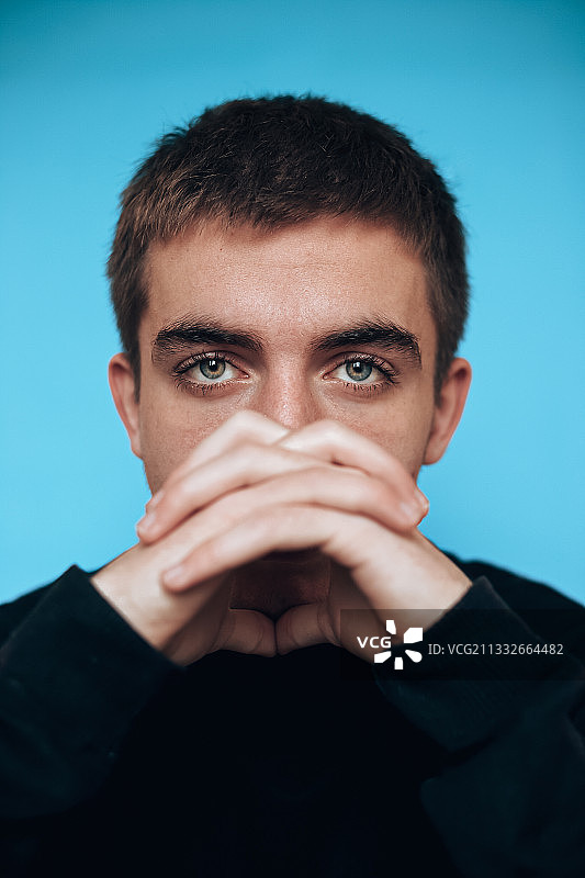 蓝色背景前的年轻男子人像图片素材