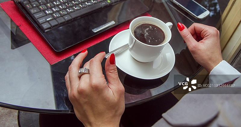 女人在桌旁手持咖啡杯的手部特写图片素材