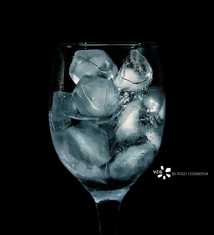 黑色背景下玻璃杯中冰块特写图片素材