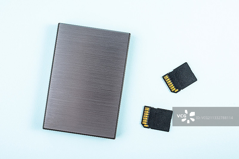 移动硬盘和存储卡在蓝色背景上图片素材