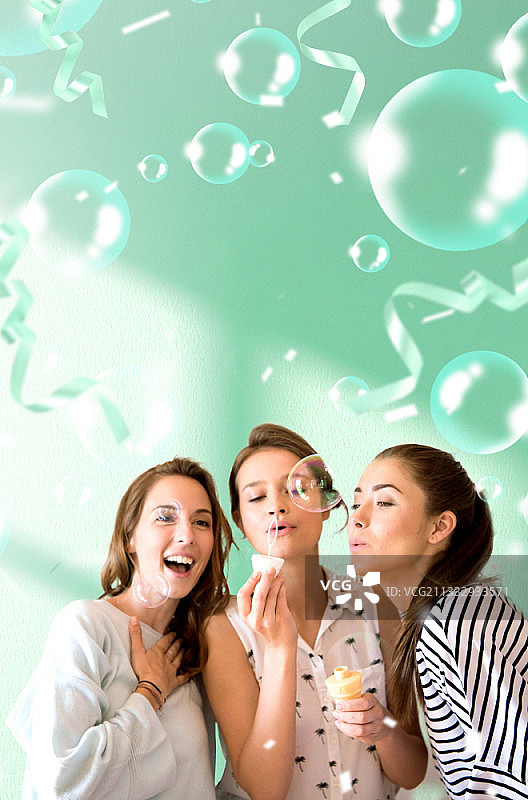 在绿色背景上吹泡泡的三个女人图片素材