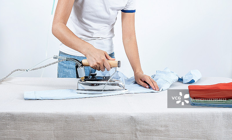 一个亚洲家庭妇女正在家里熨烫衣服图片素材