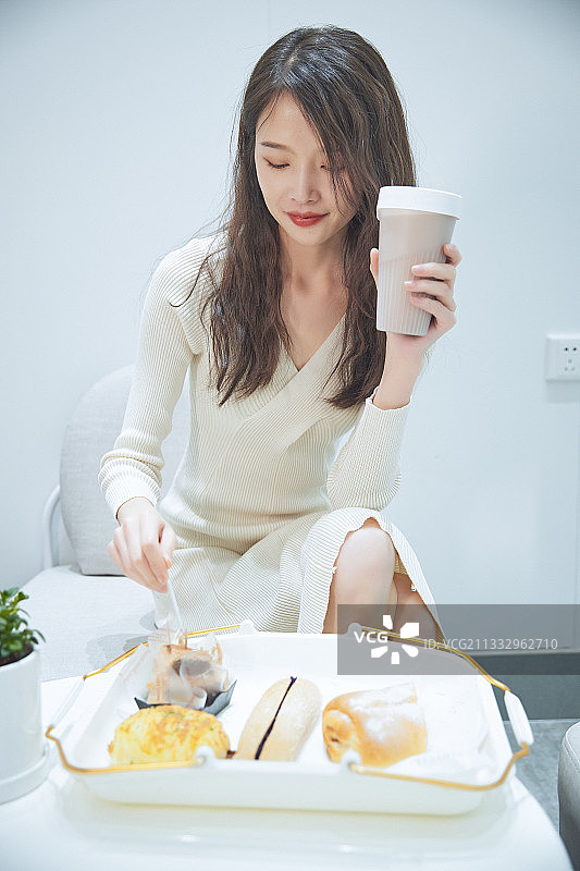 在烘焙店吃面包喝牛奶的可爱亚洲少女图片素材