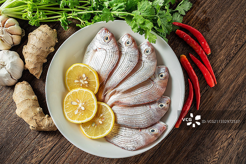 一碟新鲜红鲷鱼和香料食材在木板背景上图片素材