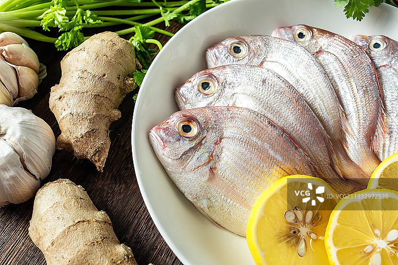 一碟新鲜红鲷鱼和香料食材在木板背景上图片素材