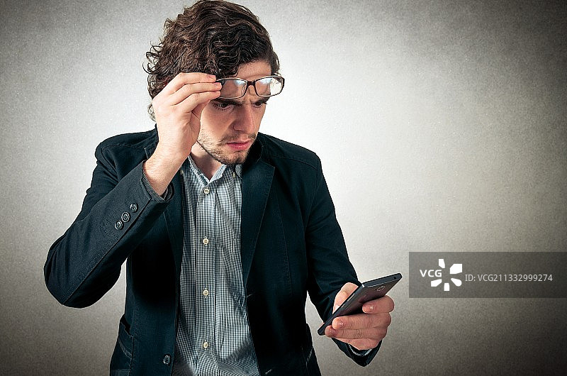 在灰色背景下使用手机的商人图片素材