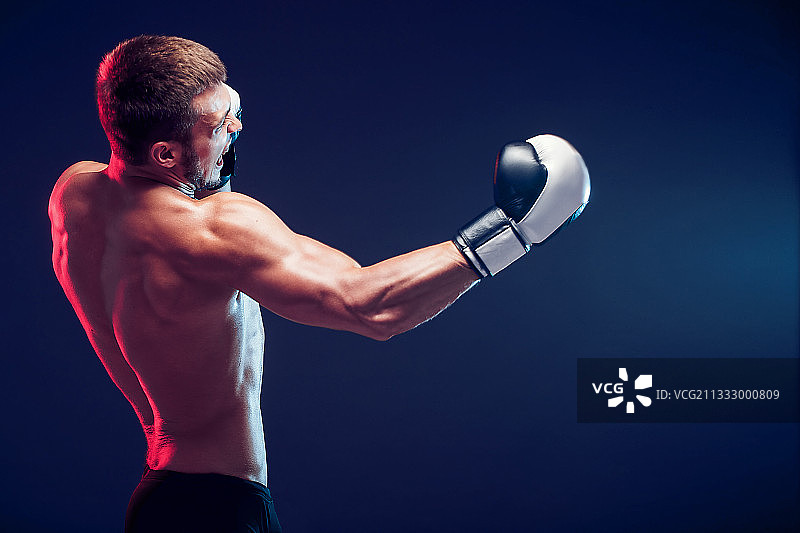 在深色背景下拳击的健壮男人图片素材