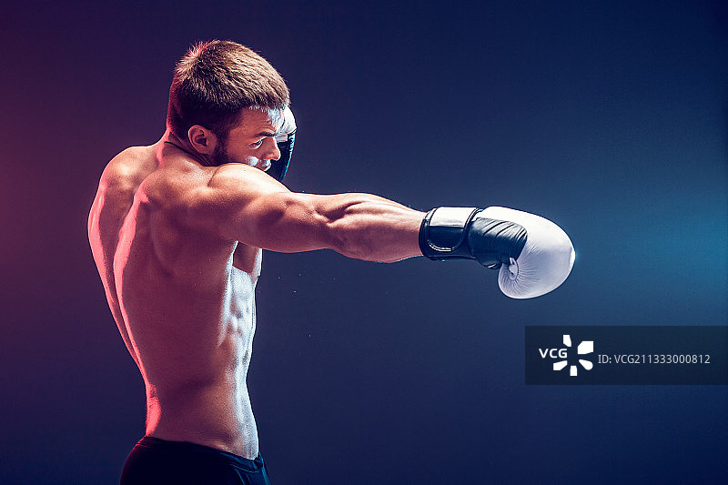 在深色背景下拳击的健壮男人图片素材