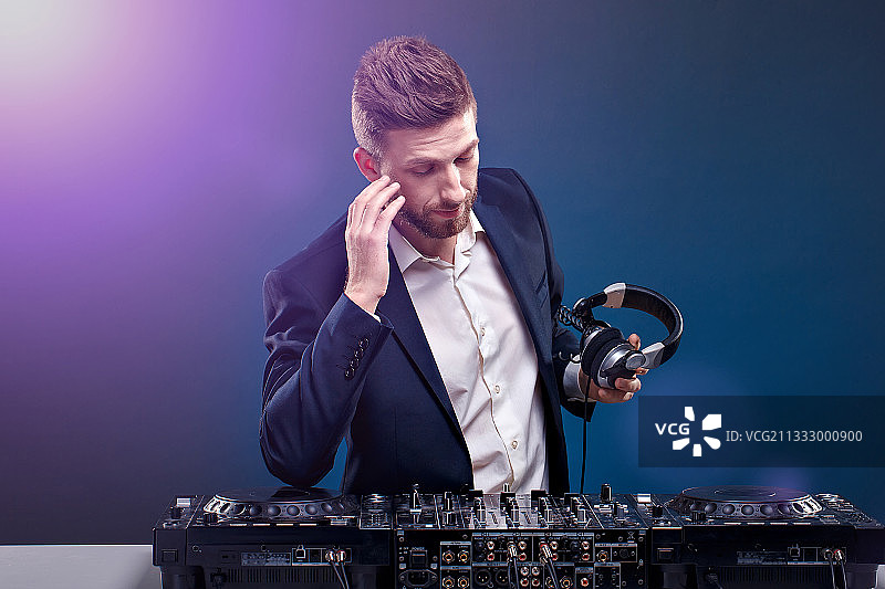 在蓝色背景下工作的年轻DJ图片素材