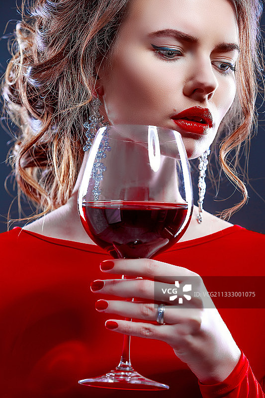 手持红酒的年轻女人，灰色背景图片素材
