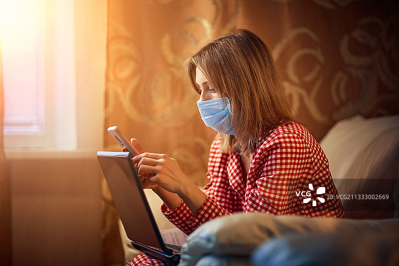 戴口罩的女人在家用笔记本电脑工作图片素材