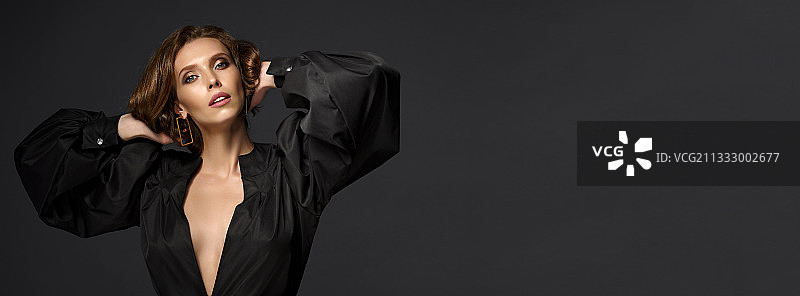 年轻女子肖像：手置于发间，黑色背景图片素材