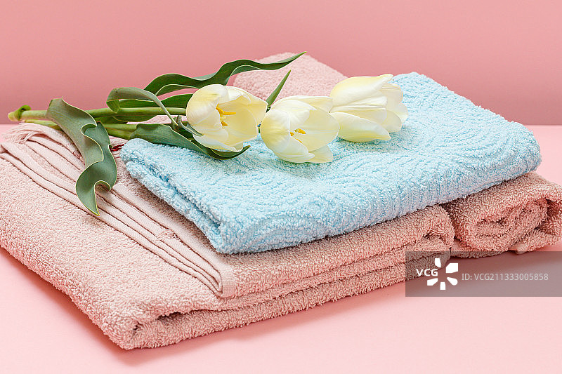 粉色背景上的毛巾和鲜花特写图片素材