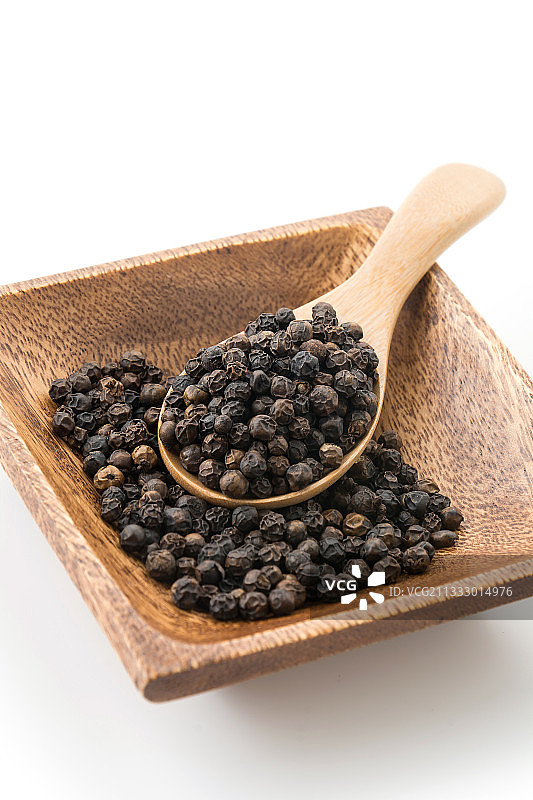 白色背景上的黑胡椒木勺特写图片素材