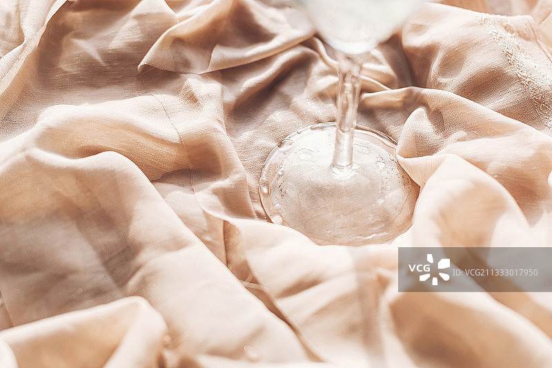 柔软米色织物上的湿酒杯和水滴图片素材