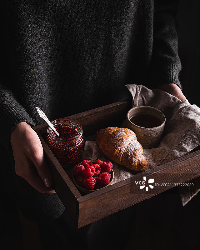 女子手拿食物的腰部特写，黑色背景图片素材