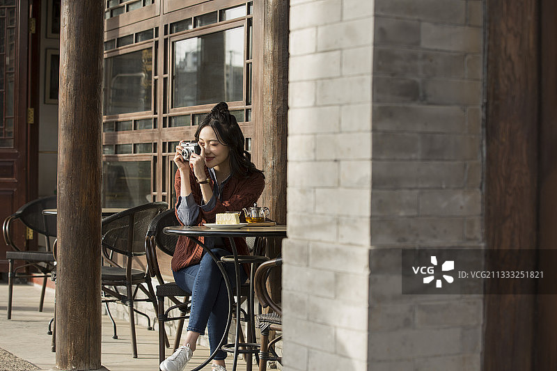 青年女子城市旅行在露天咖啡馆喝茶休息拍照图片素材