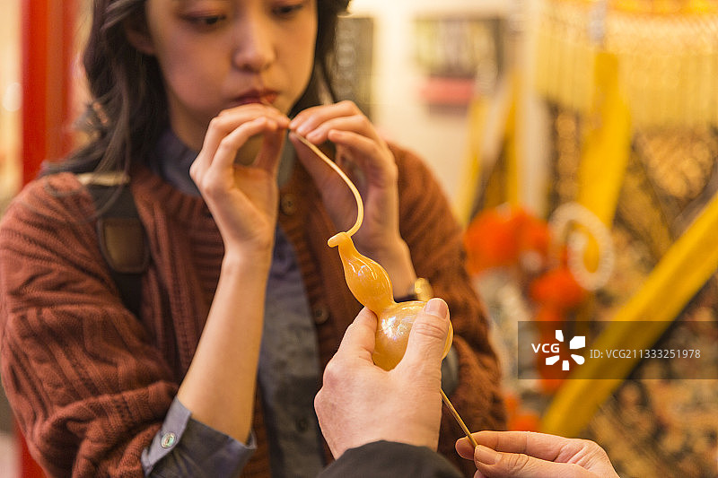 青年女子城市美食街旅行吹糖人图片素材