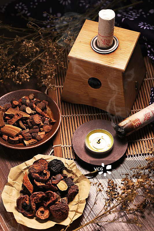 冒烟的艾灸盒和艾灸柱放在中药柜前图片素材