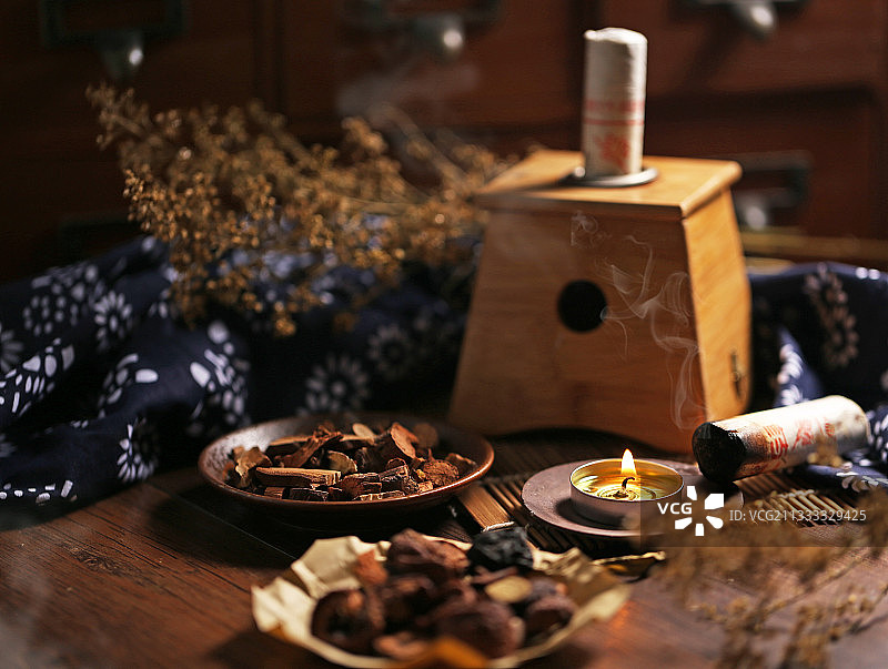 冒烟的艾灸盒和艾灸柱放在中药柜前图片素材