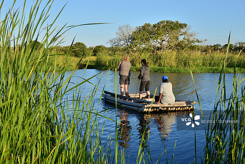 伊西曼加利索湿地公园：游客乘坐当地棕榈叶船横渡河流，南非夸祖鲁-纳塔尔省圣卢西亚图片素材