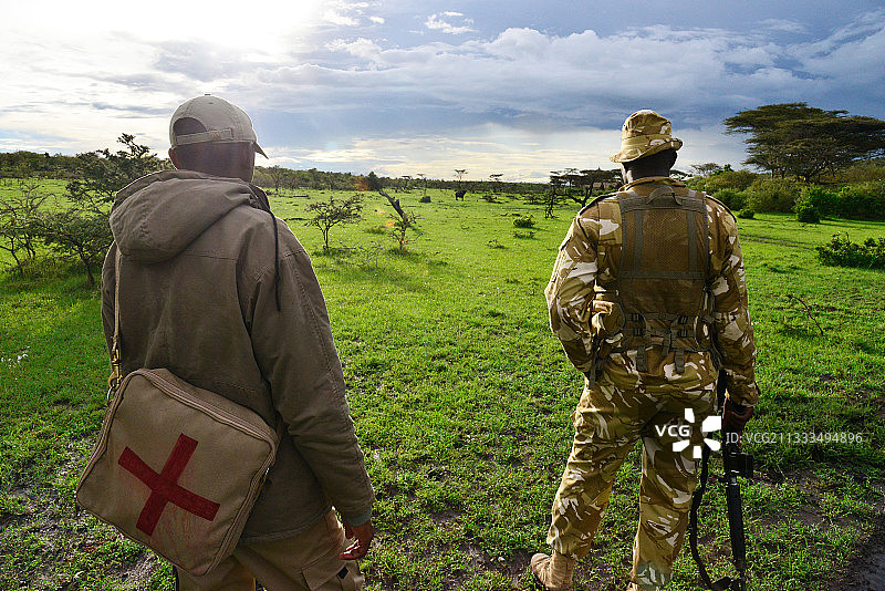 武装护林员在肯尼亚马赛马拉国家公园附近的保护区内行走图片素材