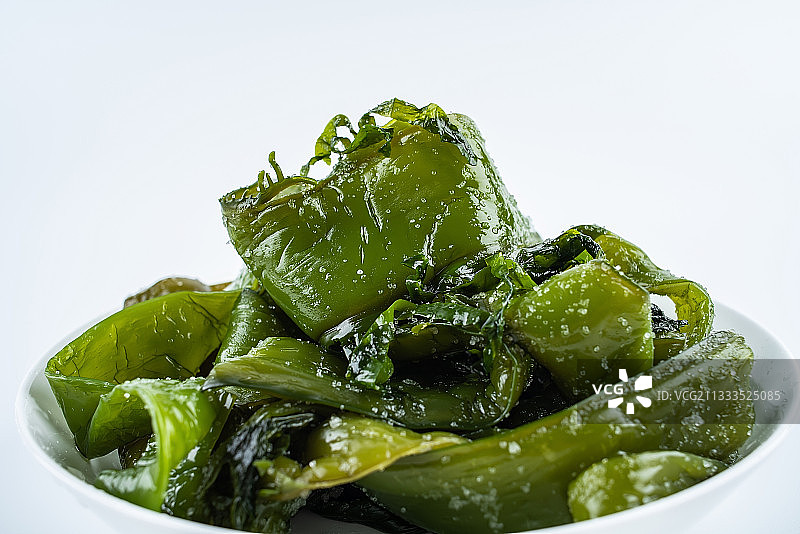 白背景上一碟新鲜绿色盐渍海白菜梗图片素材