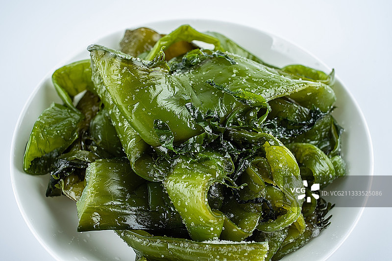 白背景上一碟新鲜绿色盐渍海白菜梗图片素材