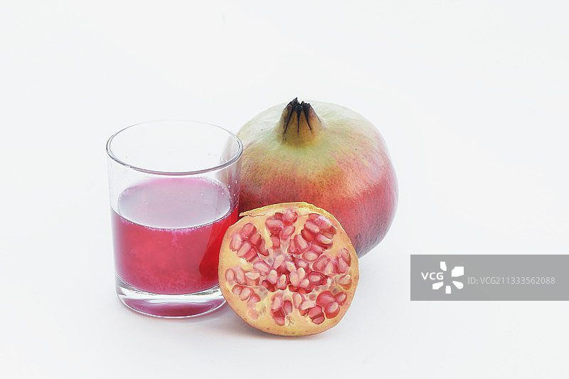 白色背景下的石榴汁、半个石榴和完整石榴图片素材