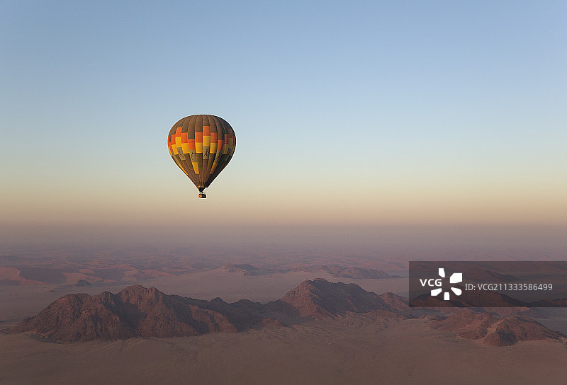 纳米布沙漠边缘干旱平原和孤立山脊上空的热气球图片素材