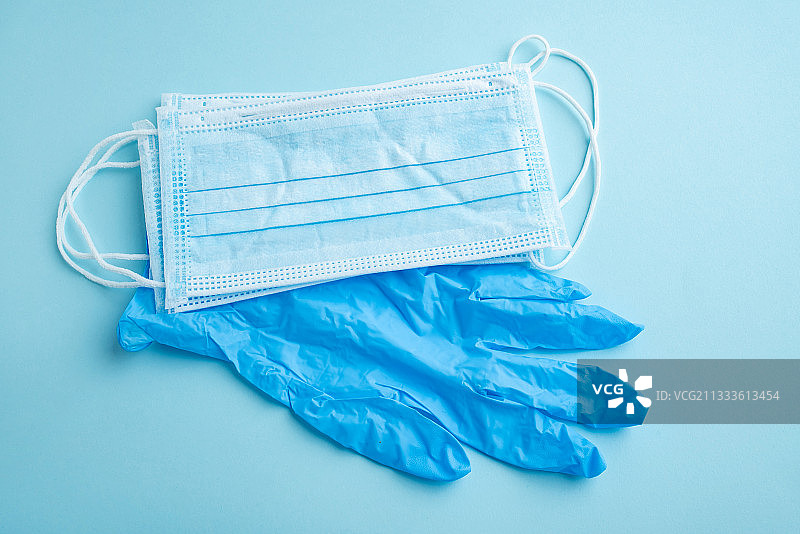 浅蓝色背景上的一次性医用口罩和手套图片素材