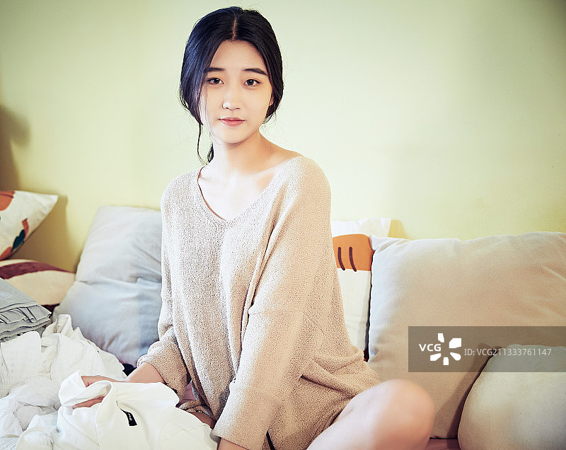 在沙发床上整理行装的年轻亚洲女性图片素材