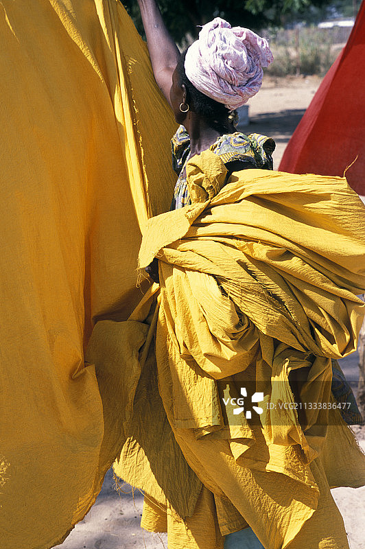 女人在达喀尔捡起一张黄色纸巾图片素材
