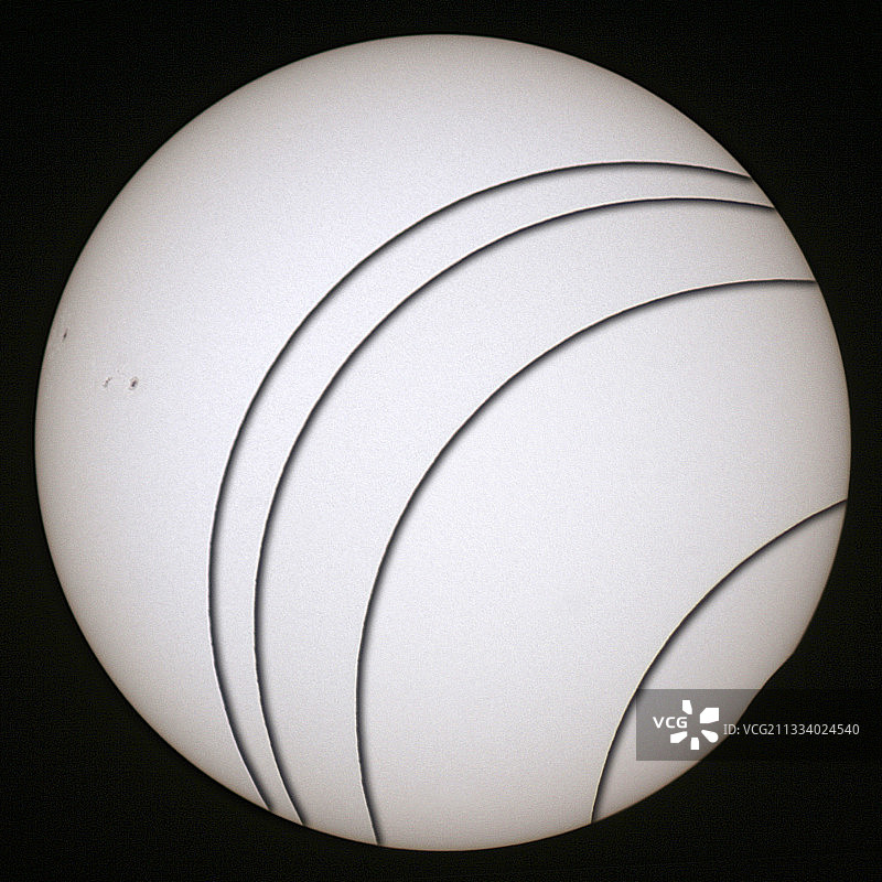 注意左下角的月球边缘：因其边缘的隆起和凹陷而不规则。左侧的黑点是太阳黑子。图片素材