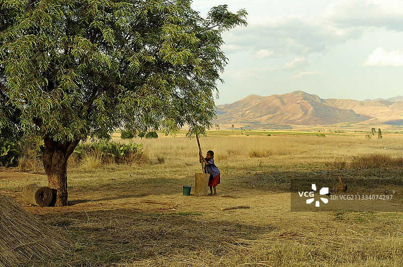 马达加斯加：女孩在研钵里研磨木薯图片素材