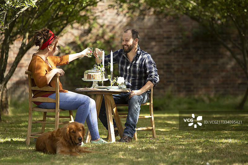 夏季花园里，和狗一起举杯的幸福情侣图片素材