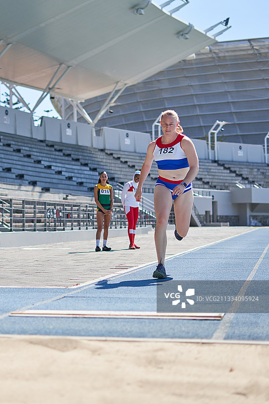 女田径运动员在阳光明媚的跑道上跳远图片素材