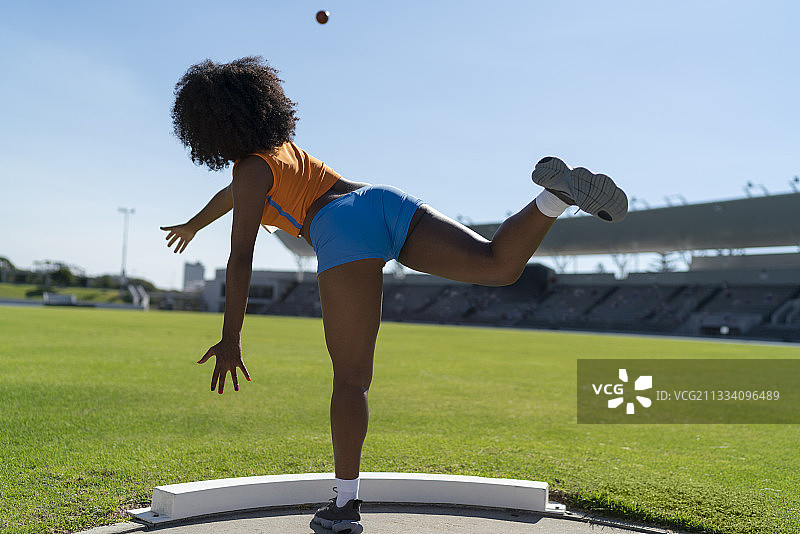 在阳光明媚的内场投掷铅球的田径女运动员图片素材