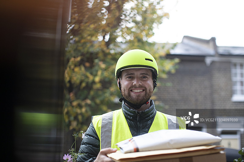 戴头盔的友好送货员在门口送包裹的肖像图片素材